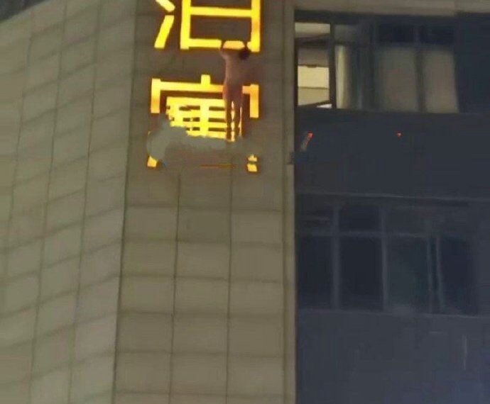 台灣新聞通訊社-玩到一半被抓姦?裸男深夜爬上酒店外招牌 街上民眾全拍下